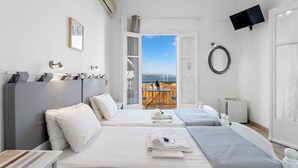 A hotel room with two beds, a TV, a ring light, and a view of the beach. - Thalassa Return To Timeless Spetses (Spetses)
