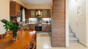 Eine moderne Küche mit Holzschränken, einem Edelstahlkühlschrank und einem Essbereich mit Holztisch und -stühlen.