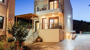 Ein modernes, zweistöckiges Haus mit Balkon, Treppe und gepflasterter Auffahrt.