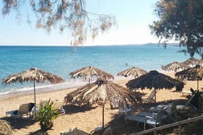 A beach with thatched umbrellas and lounge chairs. - Seaside Getaway - Aelia Villa s Dreamy Paradise (Messini)