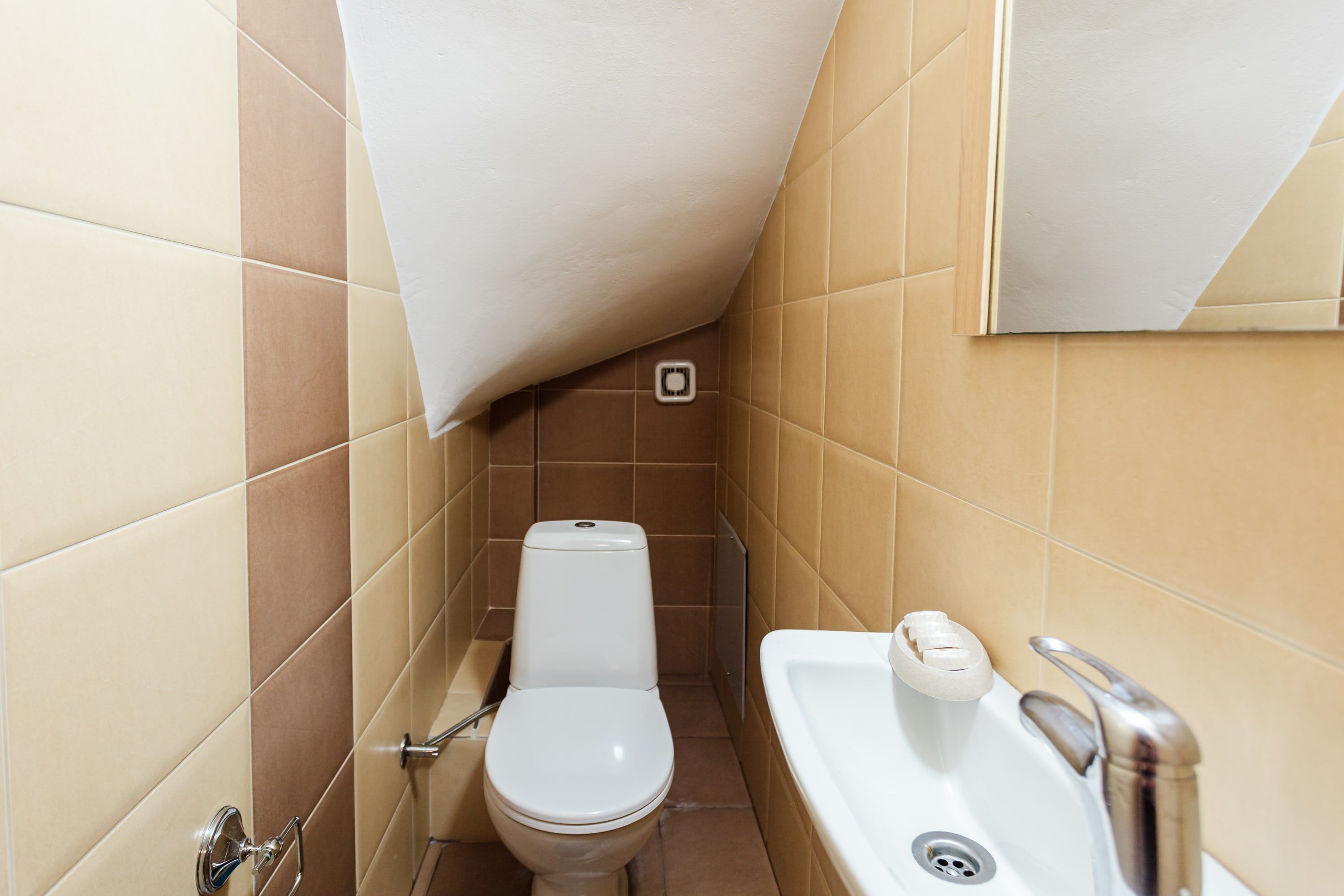 A small bathroom with a toilet, sink, and mirror.