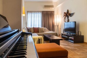 A living room with a piano, a sofa, a television, and a decorative bird sculpture. - Dancing on Sunshine - Melina s City Getaway (Kalamata)