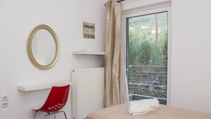 A hotel room with two beds, a red chair, a mirror, a radiator, a window with curtains, and a motivational quote on the wall. - Nina s Villa Cosy Seaview Retreat (Kalamata)