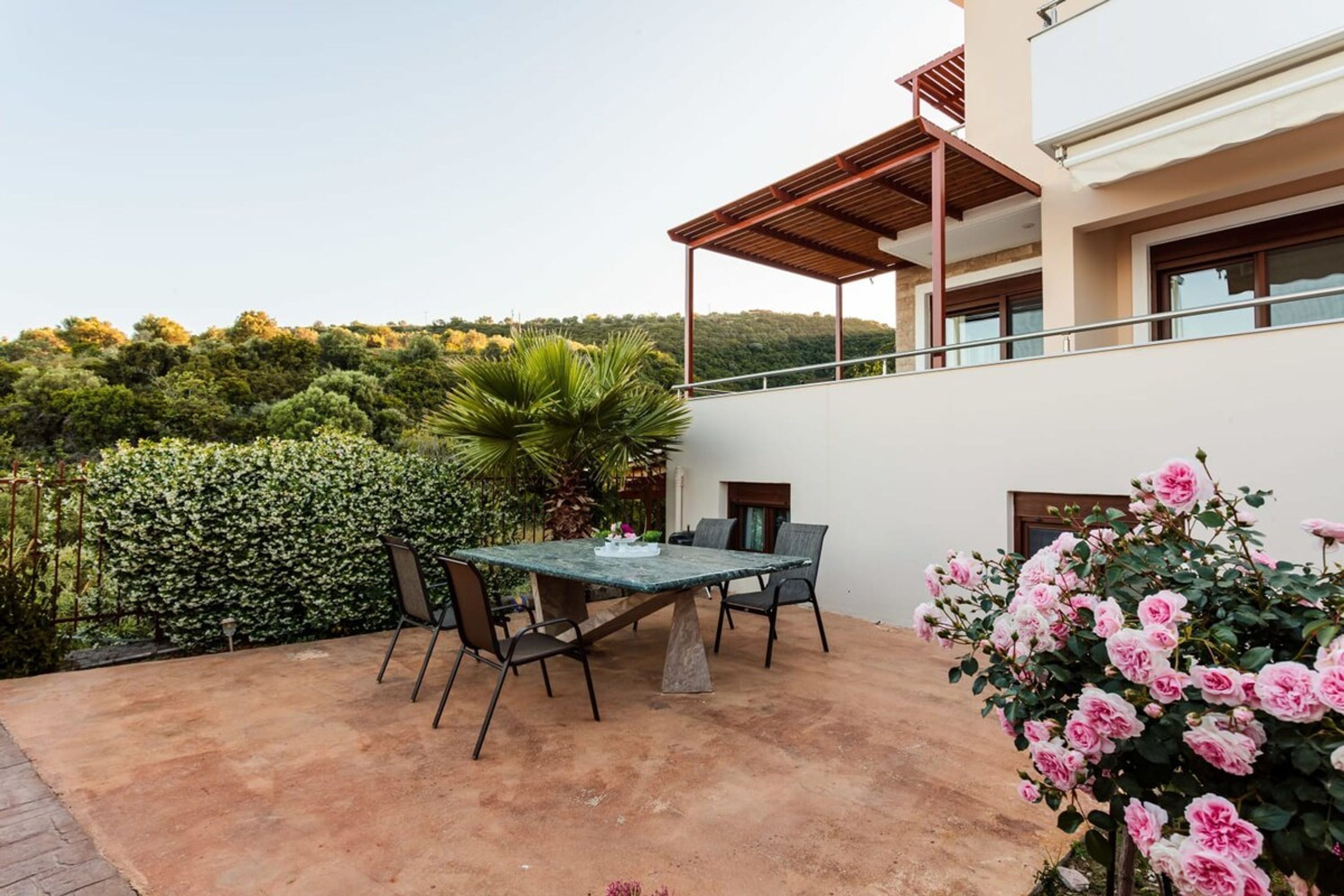 A patio with a table and chairs, surrounded by a white building with a balcony.