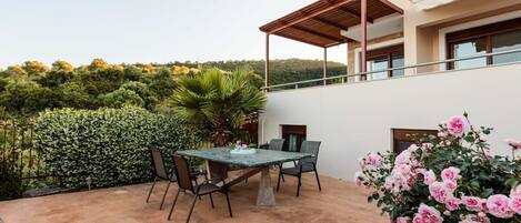 A patio with a table and chairs, surrounded by a white building with a balcony.