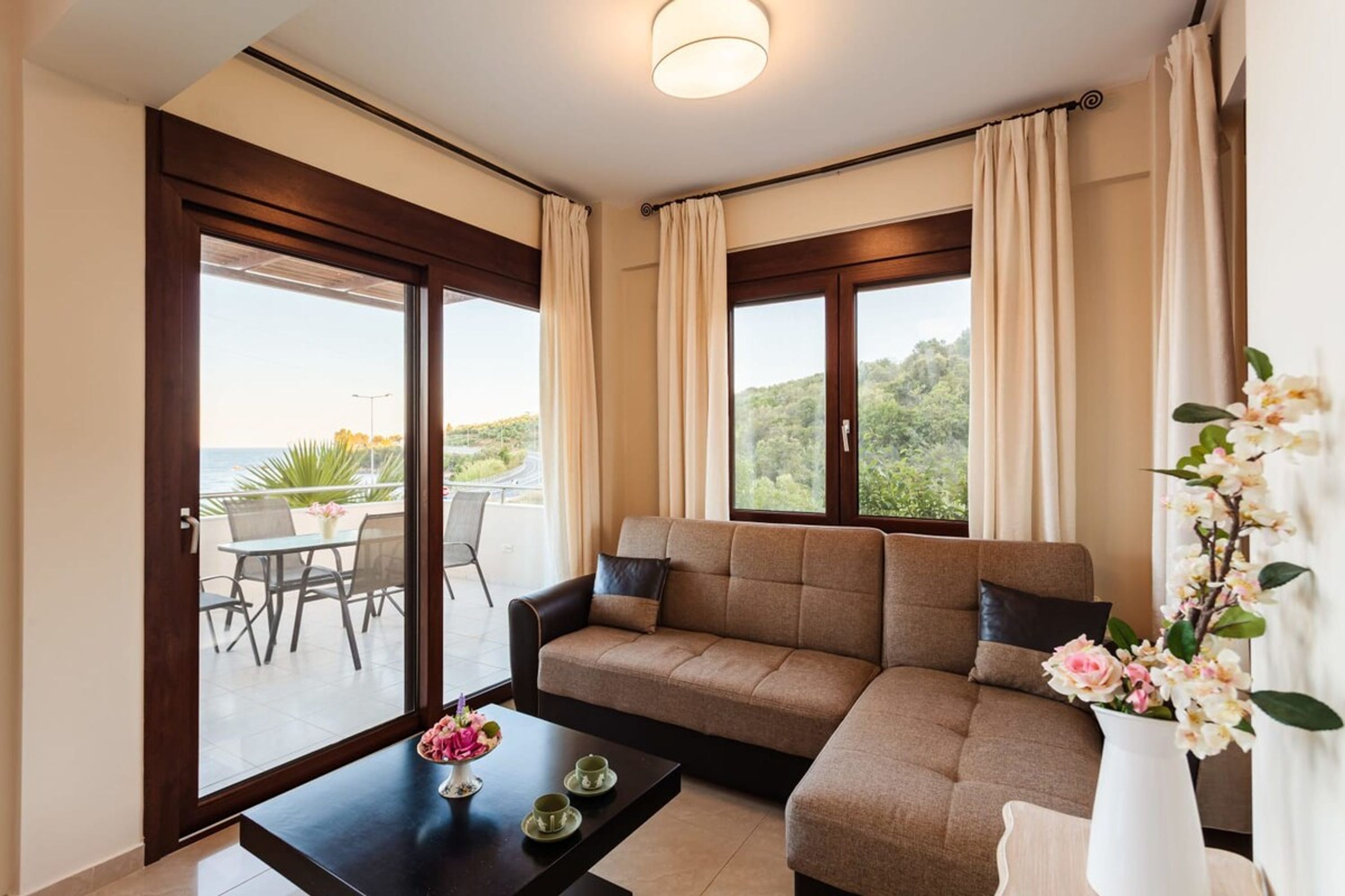 A modern living room with a sofa, a coffee table, and a view of the outdoors.