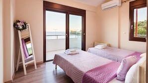 A bedroom with two beds, a balcony, and an air conditioning unit.