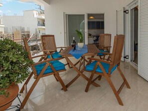 Eine Terrasse mit Tisch und Stühlen, einem Blumentopf und Blick auf die umliegenden Gebäude.