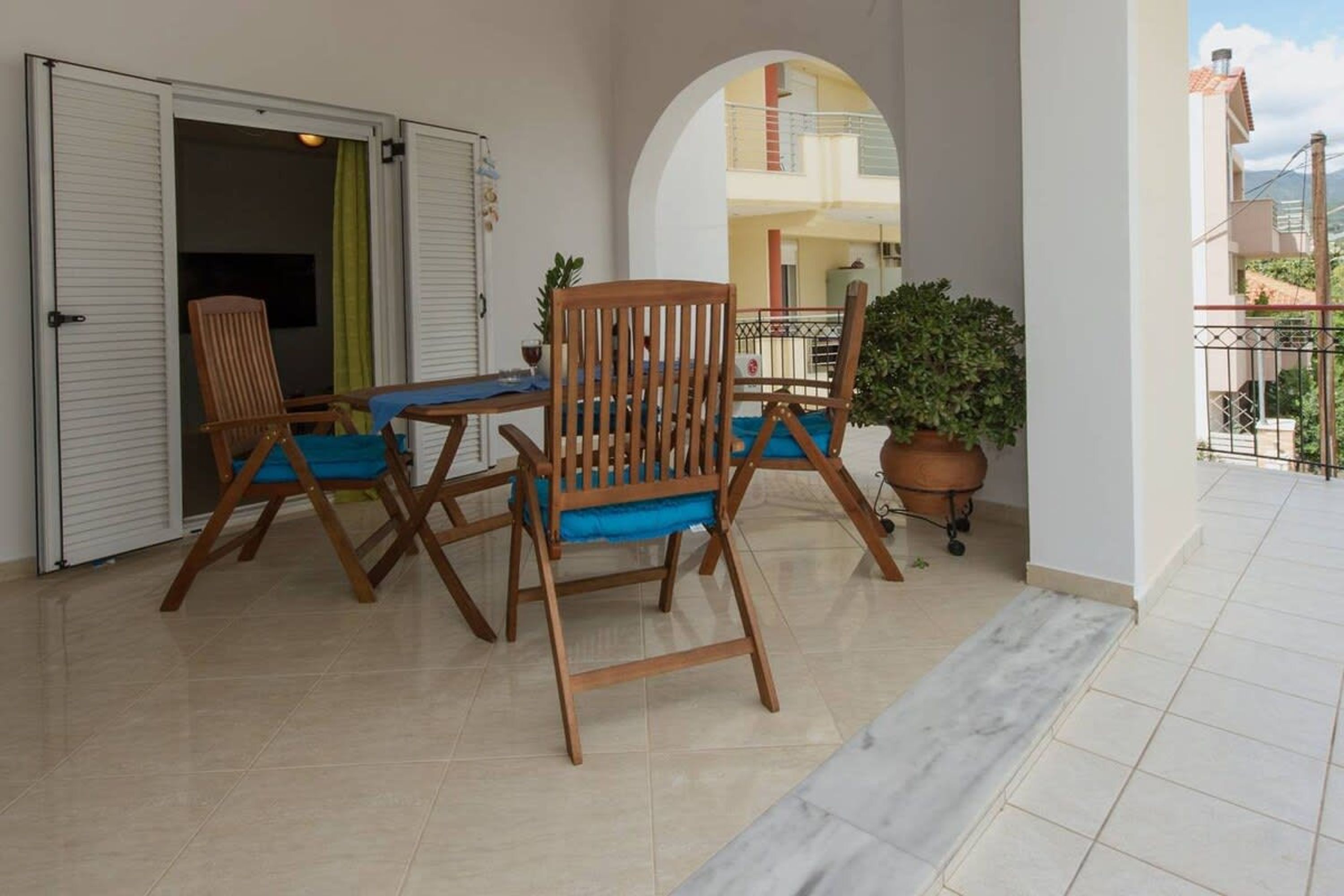 Un patio abierto con una mesa y sillas, una planta en maceta y vista de un edificio al fondo.