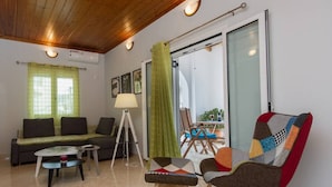 A modern living room with a sofa, a coffee table, a floor lamp, and a colorful armchair. - Thano s Stylish Flat Just 150m to the Beach (Kalamata)