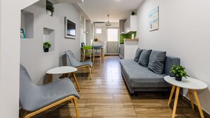 A modern living room with a grey sofa, two armchairs, a small table, and a green plant. - Citysea Fusion Elegant Gem Minutes From the Beach (Kalamata)