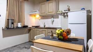 A kitchen with a dining table, chairs, a refrigerator, and a fruit bowl.