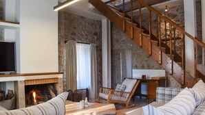 Una sala de estar acogedora con chimenea, una escalera de madera y un rincón de estar confortable.