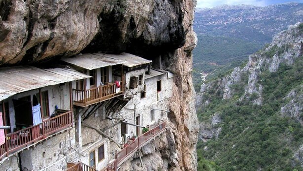 Un edificio al borde de un acantilado con varios balcones y una escalera de madera.