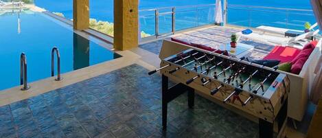 A pool table with a view of the sea and a clear sky.