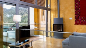 A modern living room with a fireplace, large windows, and a balcony with a pool view. - Athina Epavlis - Ethereal Charm of Blue Horizons (Platanias)