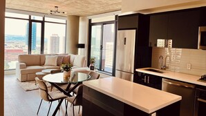 A modern kitchen with a dining area, large windows, and a city view.