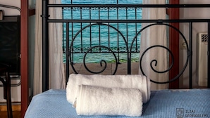 A bed with a white towel, a metal railing, and a view of the sea. - Waveside Sanctuary - Luxurious Seastone Villa (West Mani)