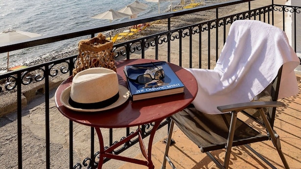 A balcony with a view of the sea, a table with a hat, sunglasses, and a book, and a chair with a towel. - Waveside Sanctuary - Luxurious Seastone Villa (West Mani)