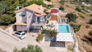 A two-story house with a swimming pool, a car parked in the driveway, and a stone wall. - Coastal Paradise Found - Komis Private Pool Gem (Zakynthos)