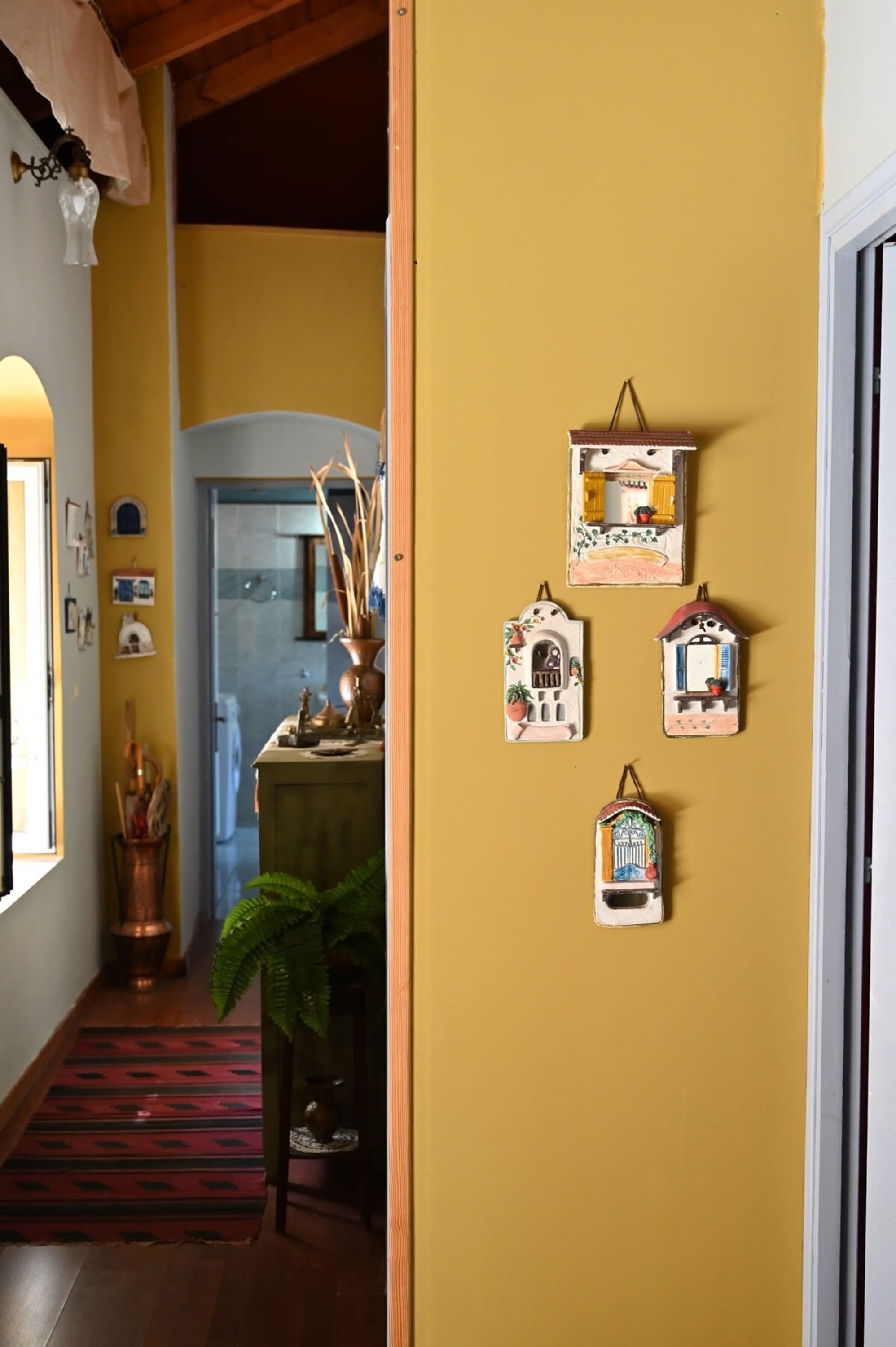 A hallway with a yellow wall, a red patterned carpet, and a door leading to a room.