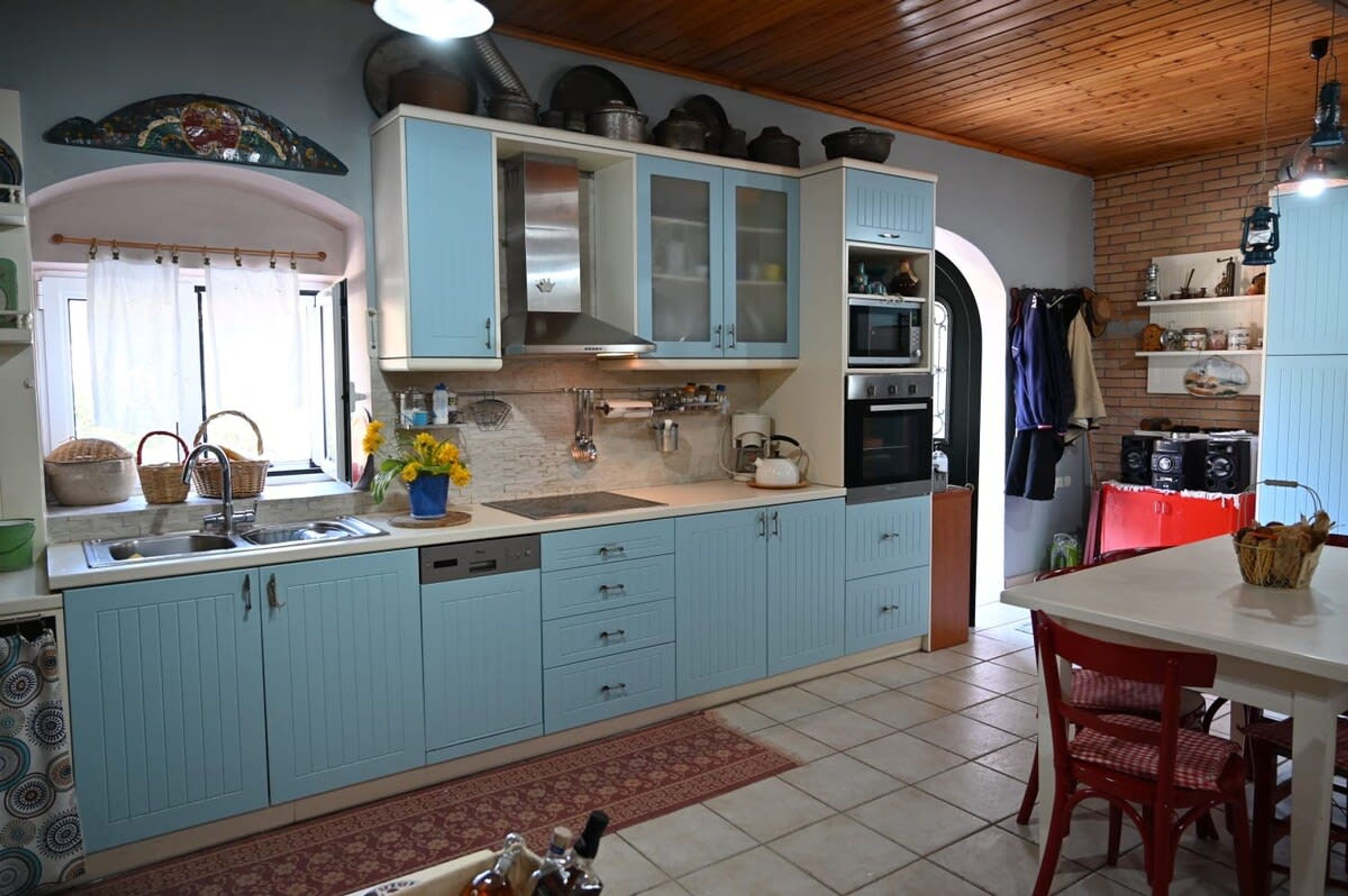 Una cocina con armarios azul claro, un fregadero, una estufa y un comedor con una mesa y sillas.