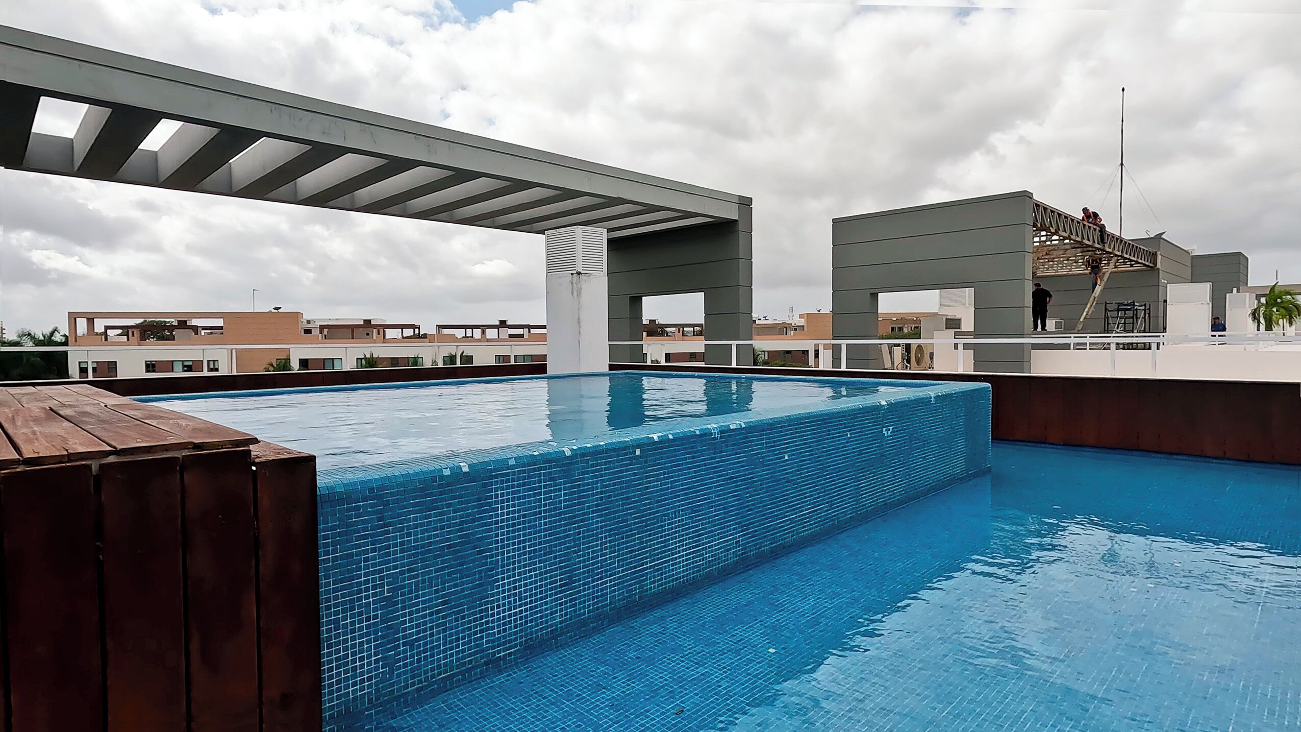 A rooftop swimming pool with a view of the cityscape and a covered walkway.