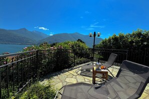 Eine Terrasse mit Blick auf Berge und einen See, ausgestattet mit Stühlen und einem Tisch.