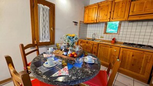 Una cocina con armarios de madera, salpicadero de azulejos y una mesa de comedor dispuesta con platos, vasos y un florero.