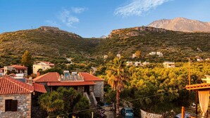A hillside village with stone buildings and red-tiled roofs, surrounded by greenery and mountains. - Mani Garden Haven - Private Retreat in Stoupa (West Mani)