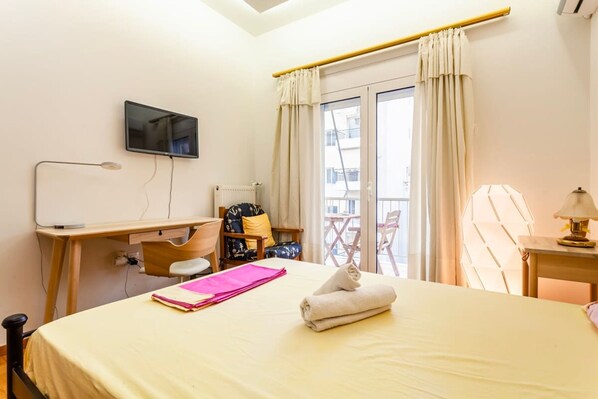 A hotel room with a bed, a desk, a chair, a TV, and a balcony with a chair. - Zografou s Hidden Gem - Athens Charming Home (Zografos)