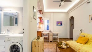 A compact living space with a washing machine, a dining area, and a sofa. - Zografou s Hidden Gem - Athens Charming Home (Zografos)