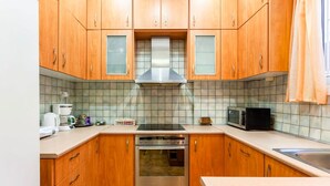A kitchen with wooden cabinets, a stainless steel range hood, a microwave, and a toaster. - Zografou s Hidden Gem - Athens Charming Home (Zografos)