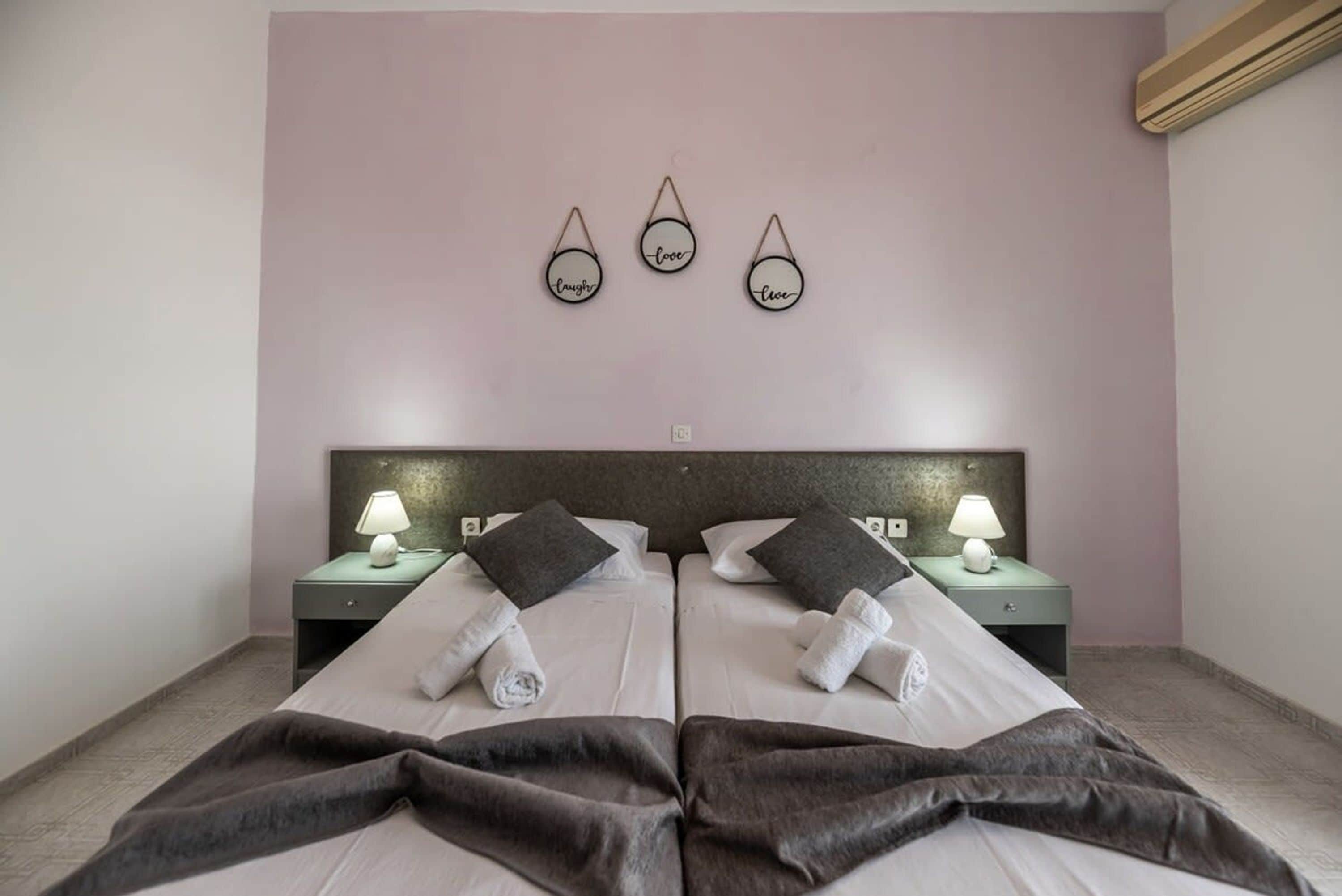 A double bed with two nightstands, each with a lamp, and a wall-mounted decoration above.