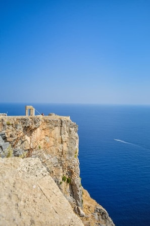 A cliffside view with a structure on the edge overlooking the sea.