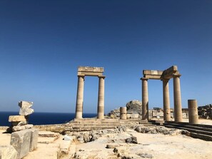 Ancient stone columns and ruins by the sea.