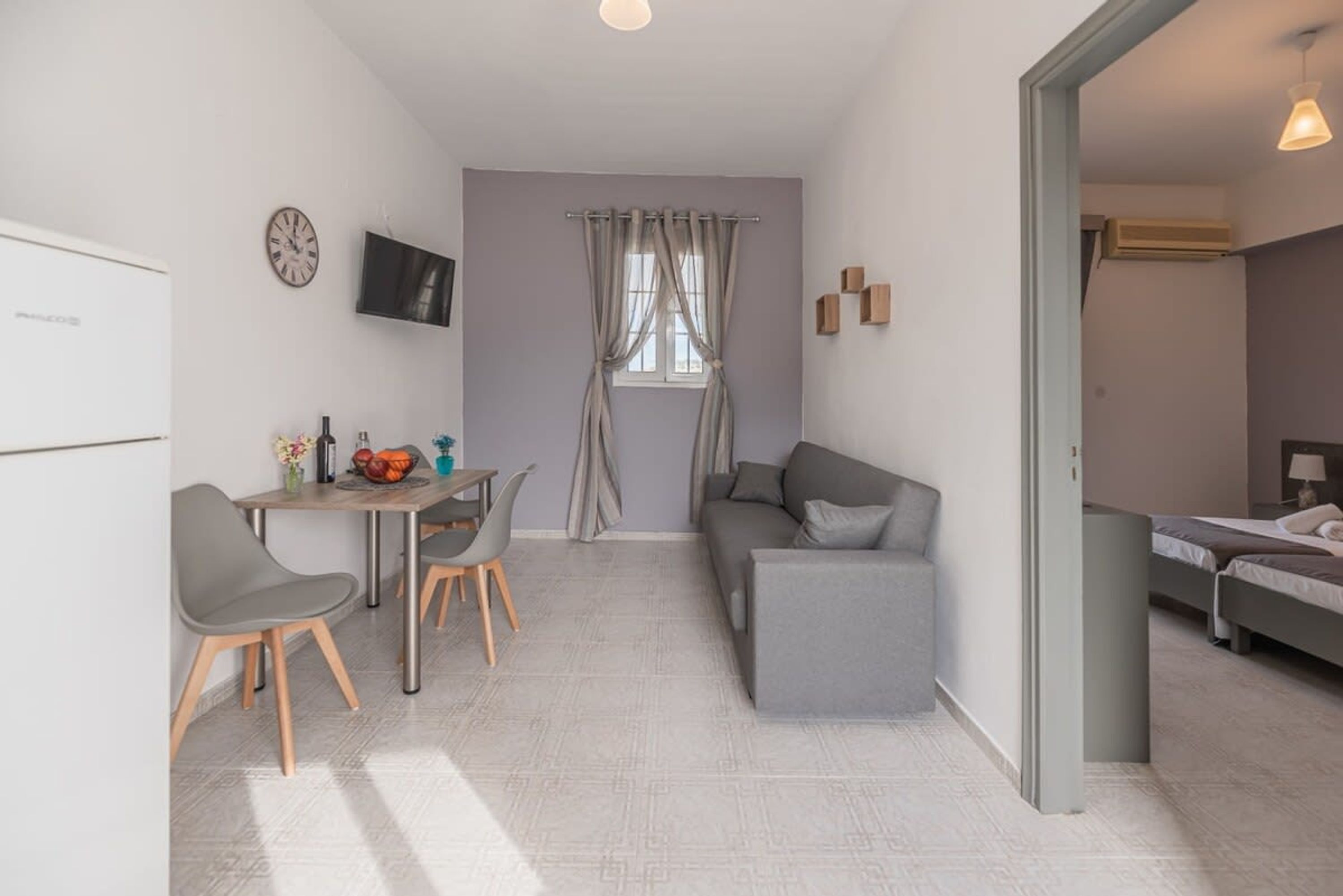 Ein kompakter Wohnraum mit Küchenzeile, Essbereich, Sofa und Bett.