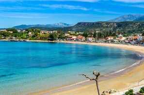 Un pueblo costero con aguas azul cristalina, playas de arena y montañas al fondo.