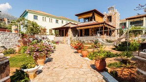 A courtyard with stone pathways, potted plants, and hammocks. - Mani s Garden Paradise - Elia Secluded Retreat (West Mani)
