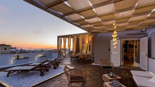 A rooftop terrace with sun loungers, wicker furniture, and a view of the sunset. - City Skyloft - Top Location Private Roof Garden (Kalamata)