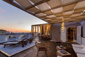 A rooftop terrace with sun loungers, wicker furniture, and a view of the sunset. - City Skyloft - Top Location Private Roof Garden (Kalamata)