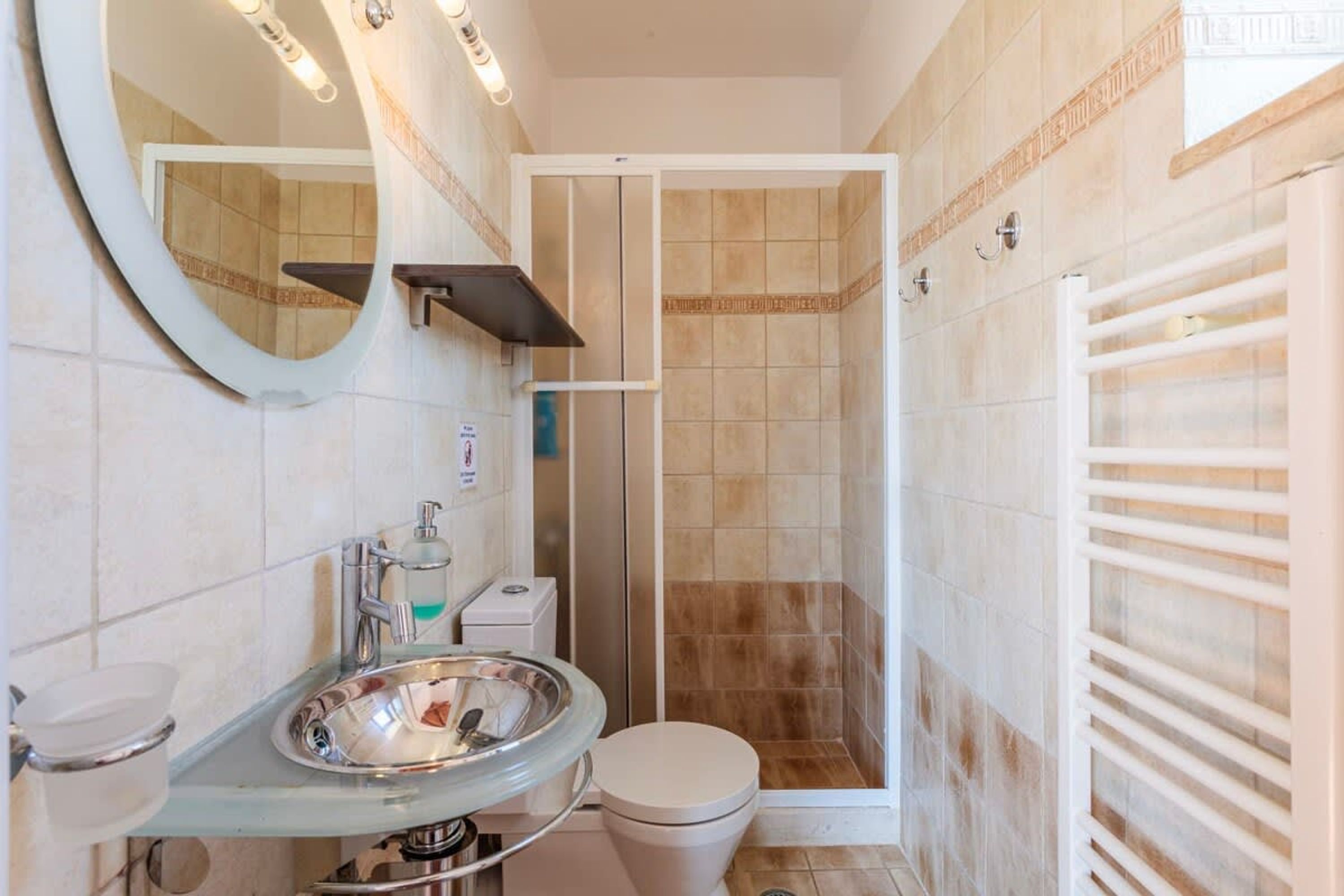 Ein Badezimmer mit einem Waschbecken aus Glas, einer Toilette, einer Duschkabine und einem Handtuchhalter.