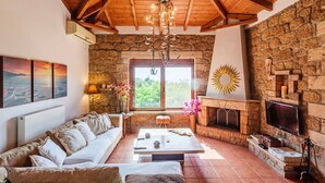 Un accogliente soggiorno con camino in pietra, soffitto in legno e una grande finestra.