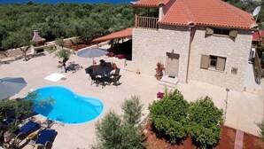 A stone villa with a pool, outdoor seating, and a view of the sea.