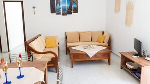 A living room with a sofa, a wooden coffee table, and a TV stand. - Atlantic Cave Haven-seaside Fully Equipped (Rhodes)