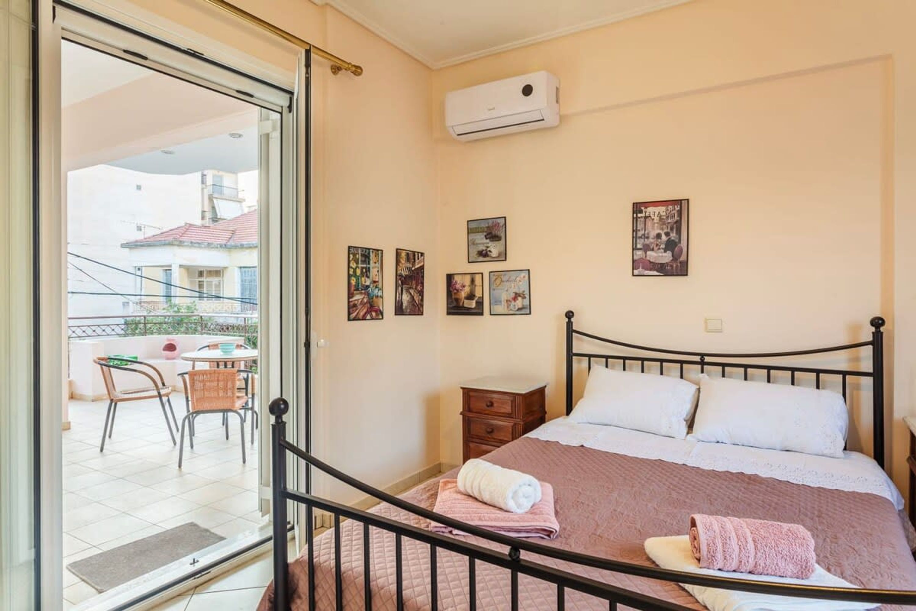 A bedroom with a bed, a nightstand, a chair, and a table with chairs outside the door.