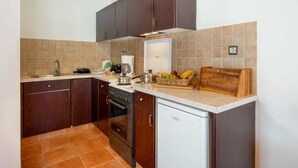 Una cocina compacta con armarios de madera oscura, una encimera blanca y un salpicadero de azulejos.