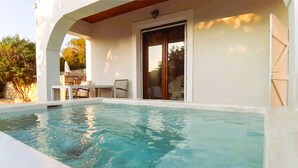 Una piscina con un patio, una mesa y sillas.