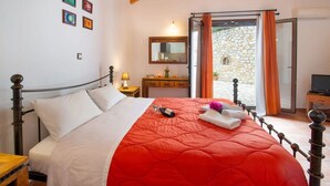 Un dormitorio con cama, mesita de noche, cómoda, espejo y televisor.