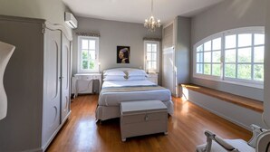 Ein Schlafzimmer mit Bett, Sitzbank, Kommode und Fenster mit Blick.